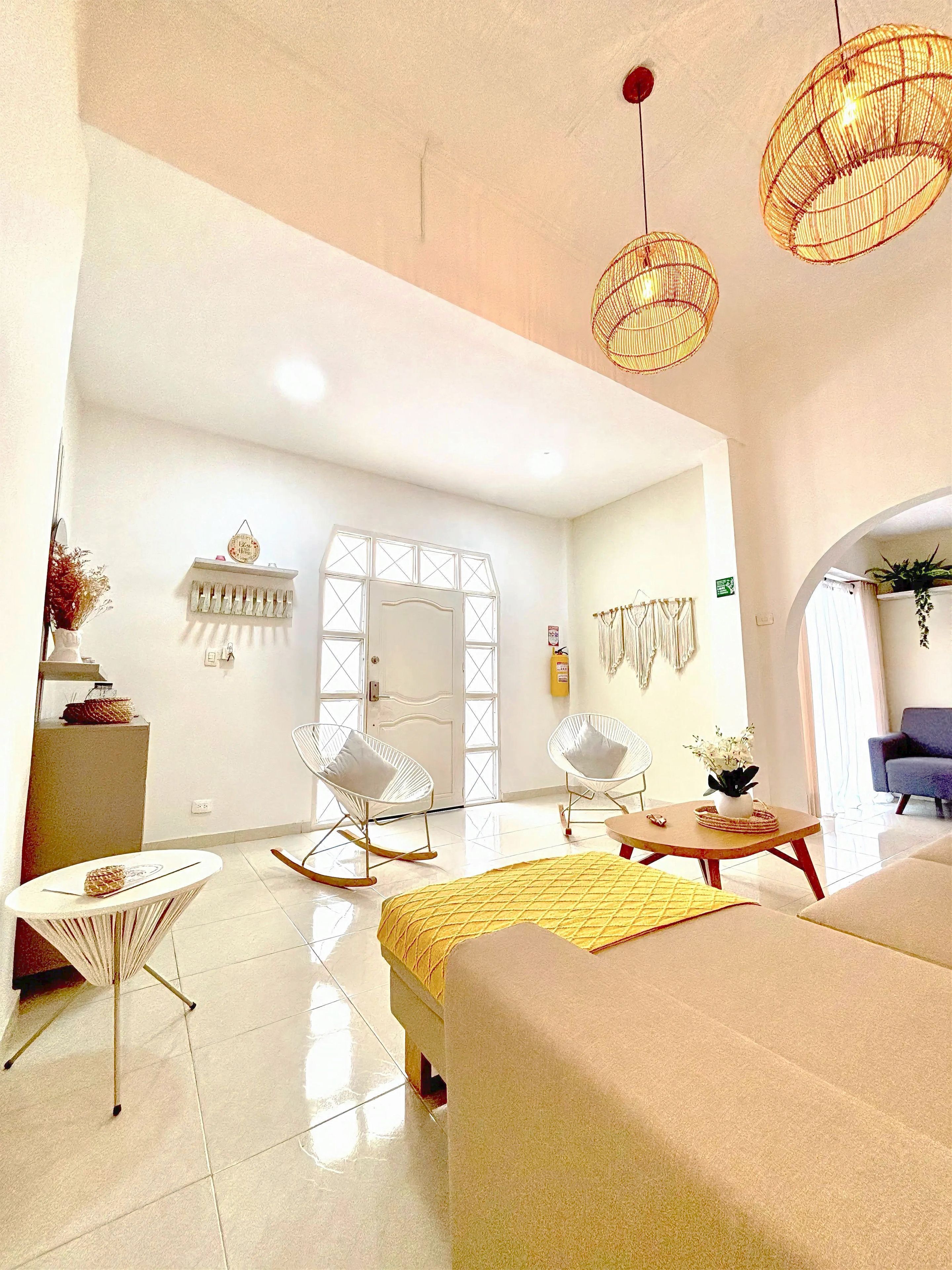 Habitación de hotel moderna con una cama, dos sillones mecedores, una mesita y un detalle decorativo en la pared.