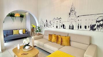 Una sala de estar moderna con un sofá, una mesa de centro y un mural de un paisaje urbano.