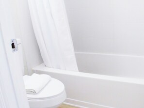 Ein helles Badezimmer mit Toilette, Duschbereich und Badewanne.