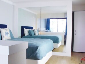 Ein Schlafzimmer mit zwei Betten, einem großen Spiegel und Blick auf einen Balkon.