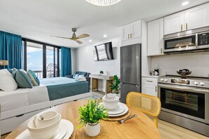 Eine moderne Küche mit Flachbildfernseher, Edelstahlgeräten und einer Essecke mit Holztisch und -stühlen.