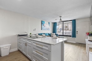 Une cuisine moderne avec des meubles blancs, un îlot central et un coin repas offrant une vue sur la ville.