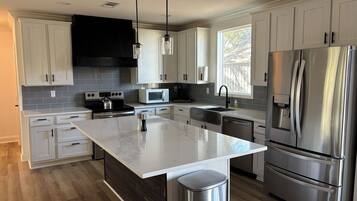 A modern kitchen with white cabinets, stainless steel appliances, and a marble island.