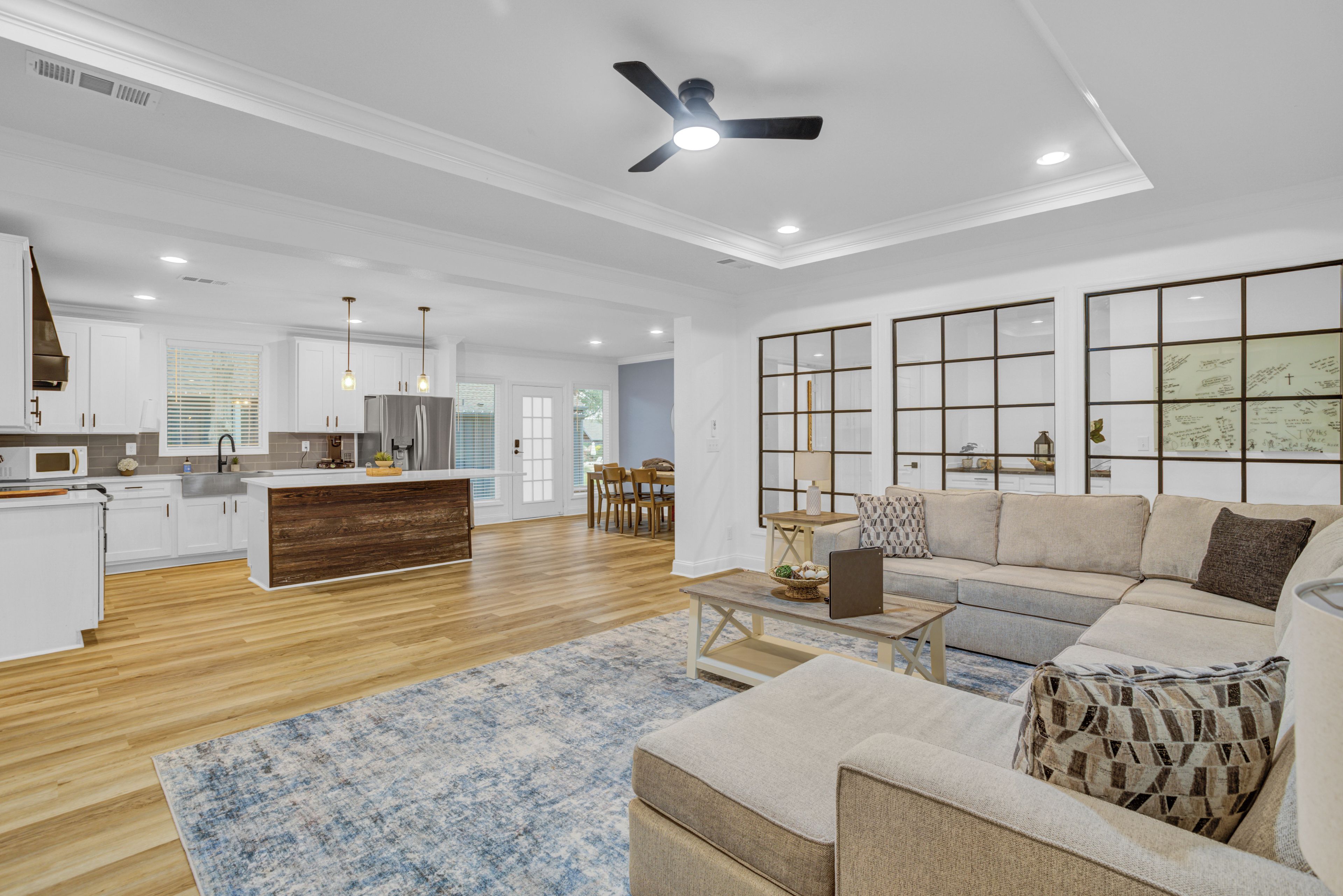 A spacious living area with a sofa, coffee table, and a kitchen in the background.