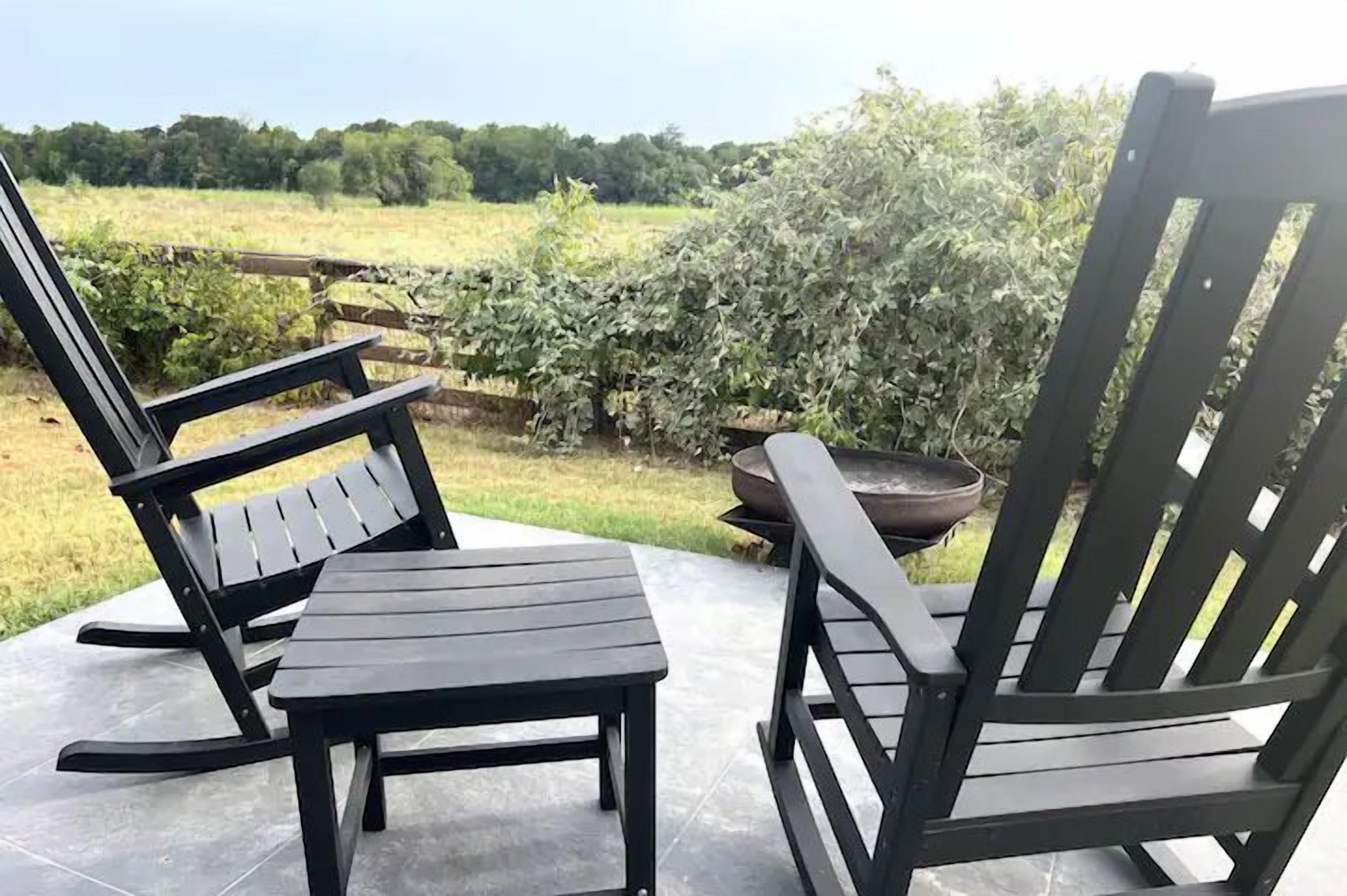 To træstole på en terrasse med udsigt over et grønt landskab.