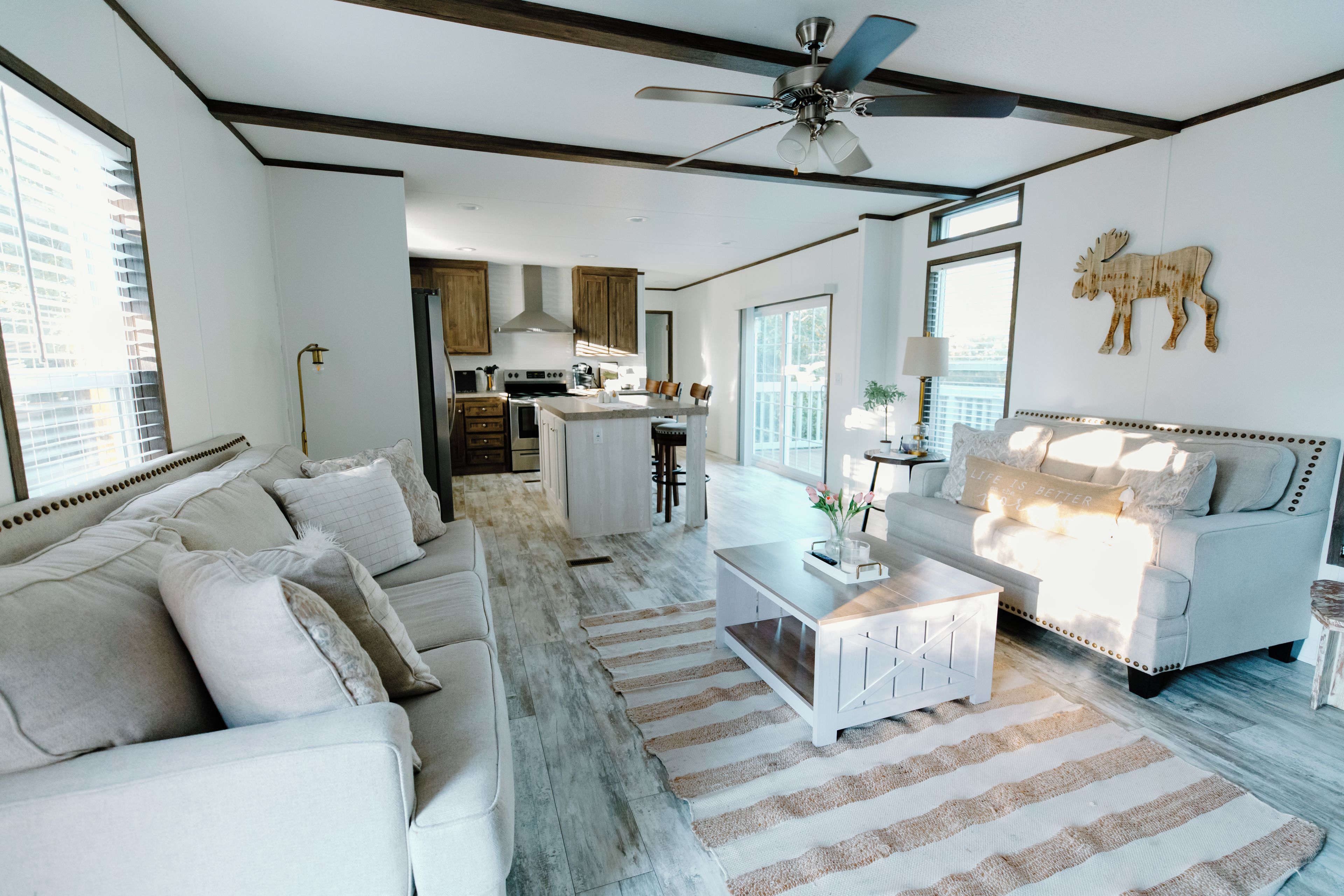 A spacious living area with a white sofa, a coffee table, and a ceiling fan.