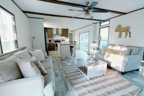A spacious living area with a white sofa, a coffee table, and a ceiling fan.