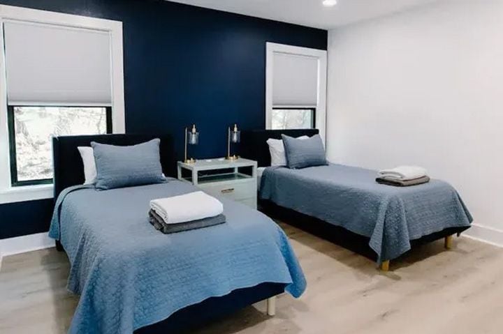Un dormitorio con dos camas, una mesita de noche y una ventana.