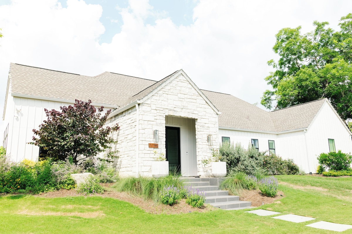 A white building with a stone facade, a front door, and a small set of steps leading to the entrance.