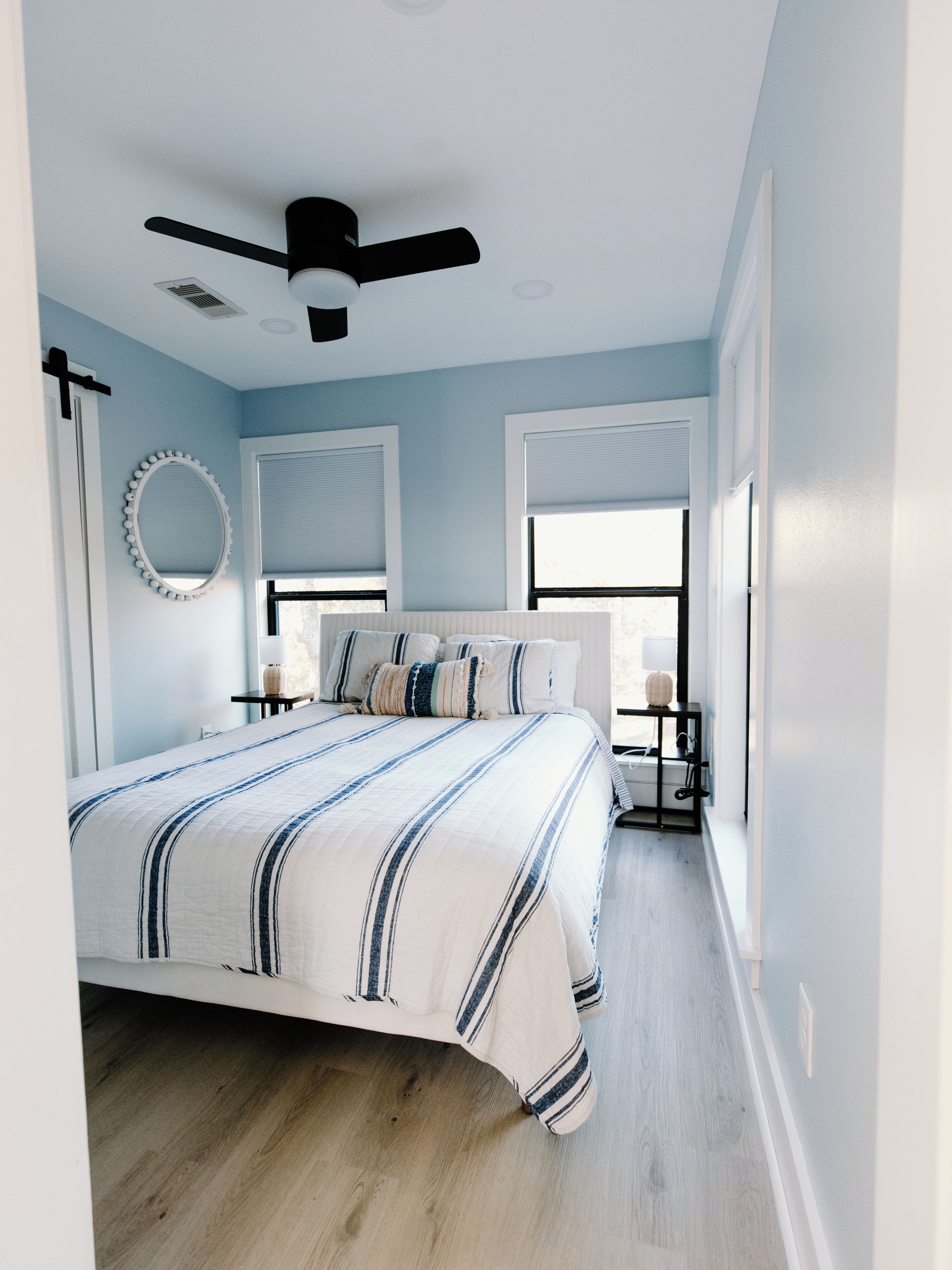 A bedroom with a bed, a ceiling fan, a window, and a bedside table.
