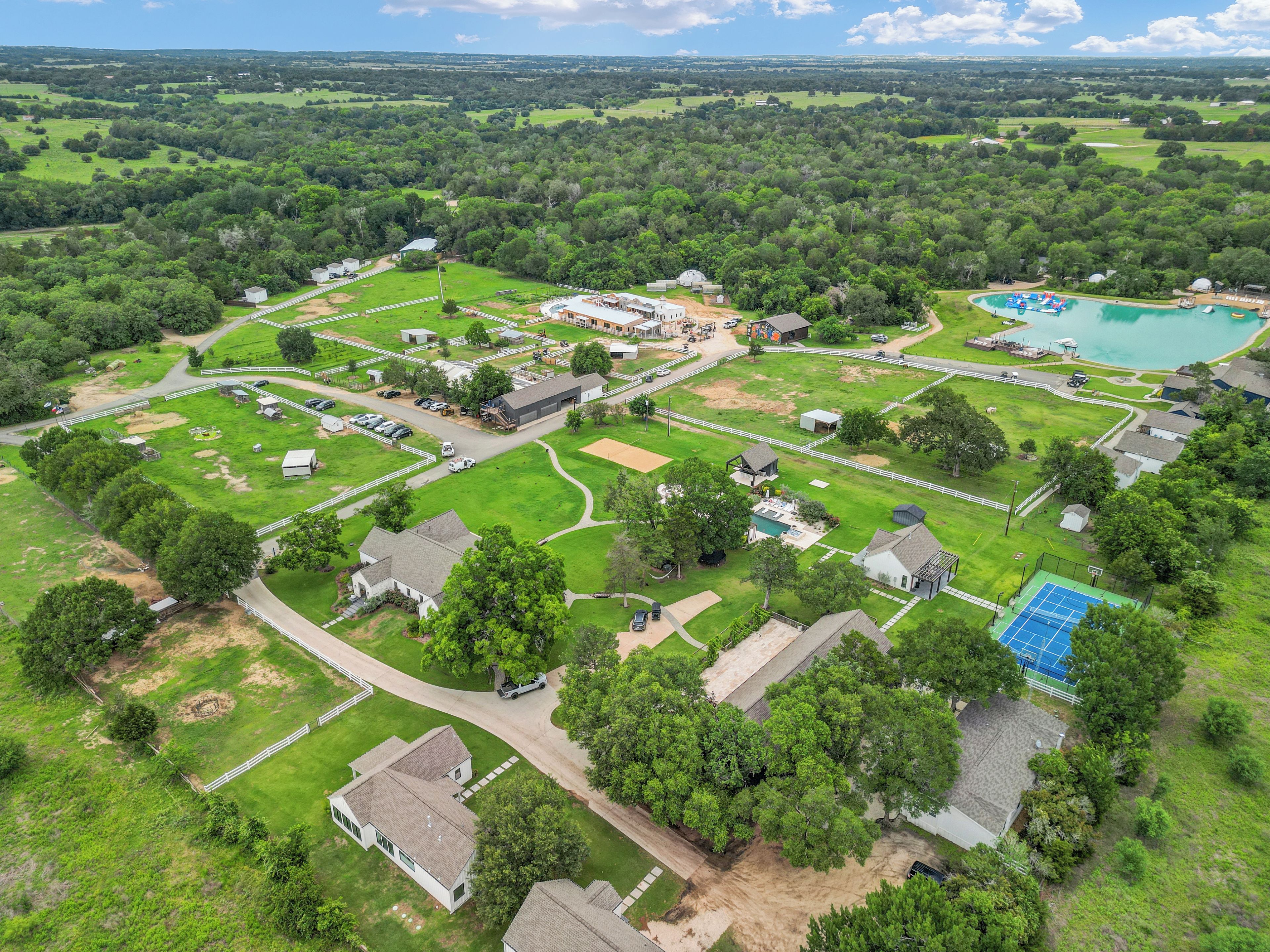 Vista aérea de una zona residencial con casas, piscina y cancha de tenis.