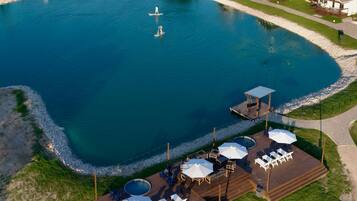 An aerial view of a resort with a large swimming pool, lounge areas, and a dock.