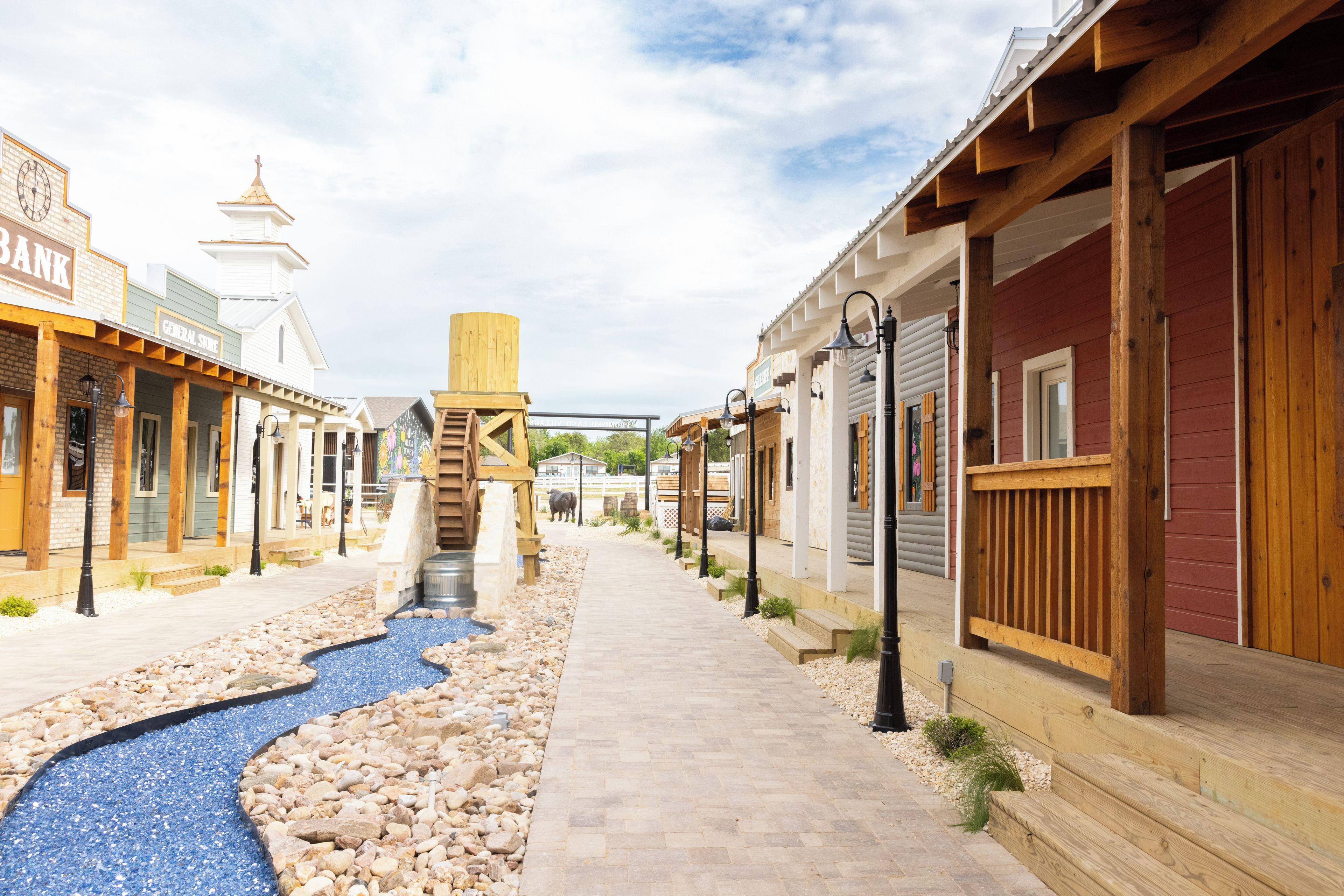 A pedestrian street with buildings on either side, a small water feature, and a wooden structure in the center.