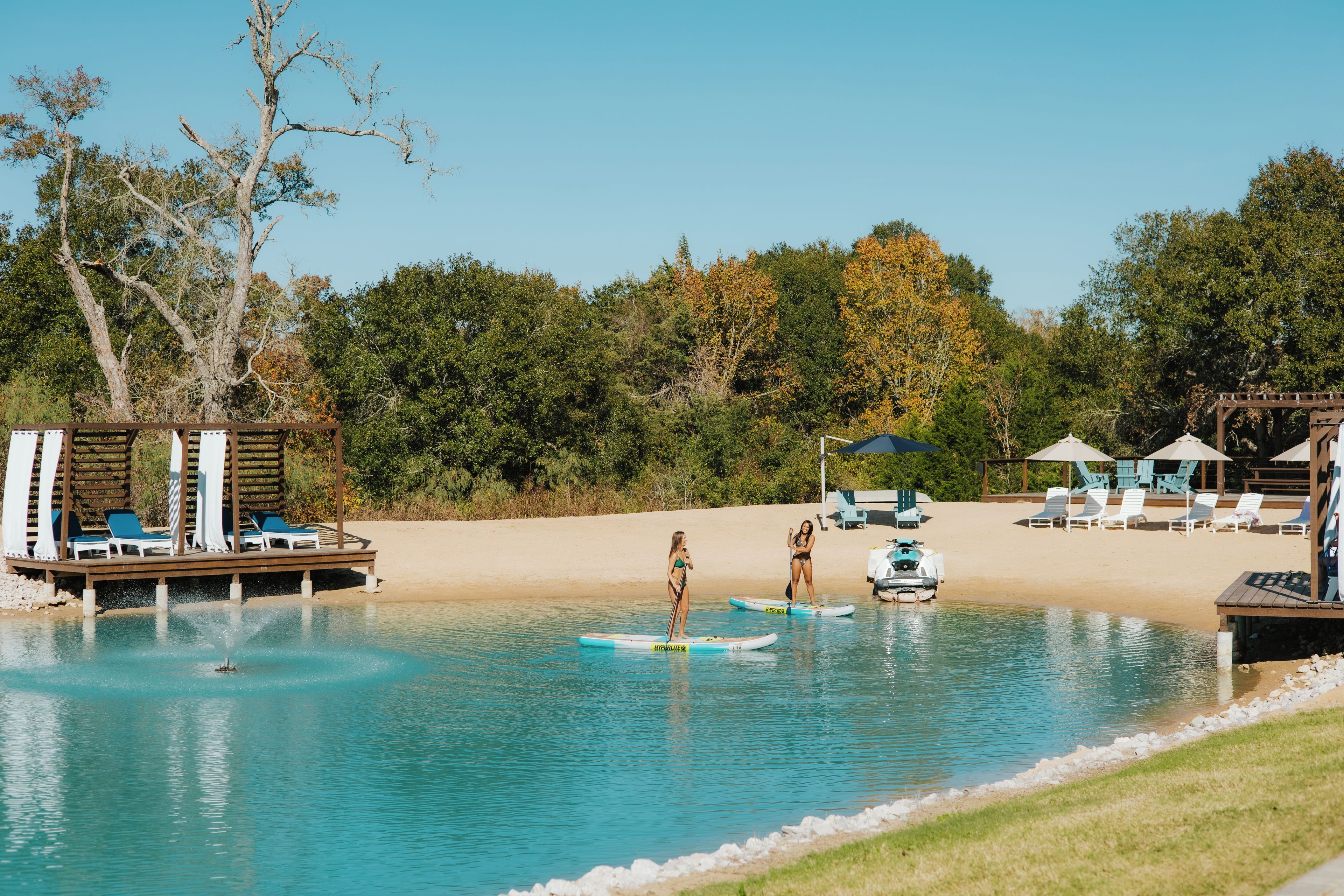 A pool area with lounge chairs, a wooden deck, and a sandy beach.