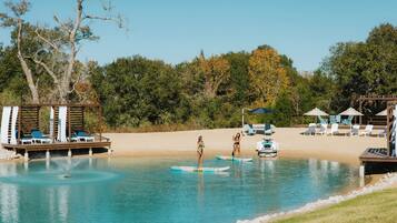 A pool area with lounge chairs, a wooden deck, and a sandy beach.