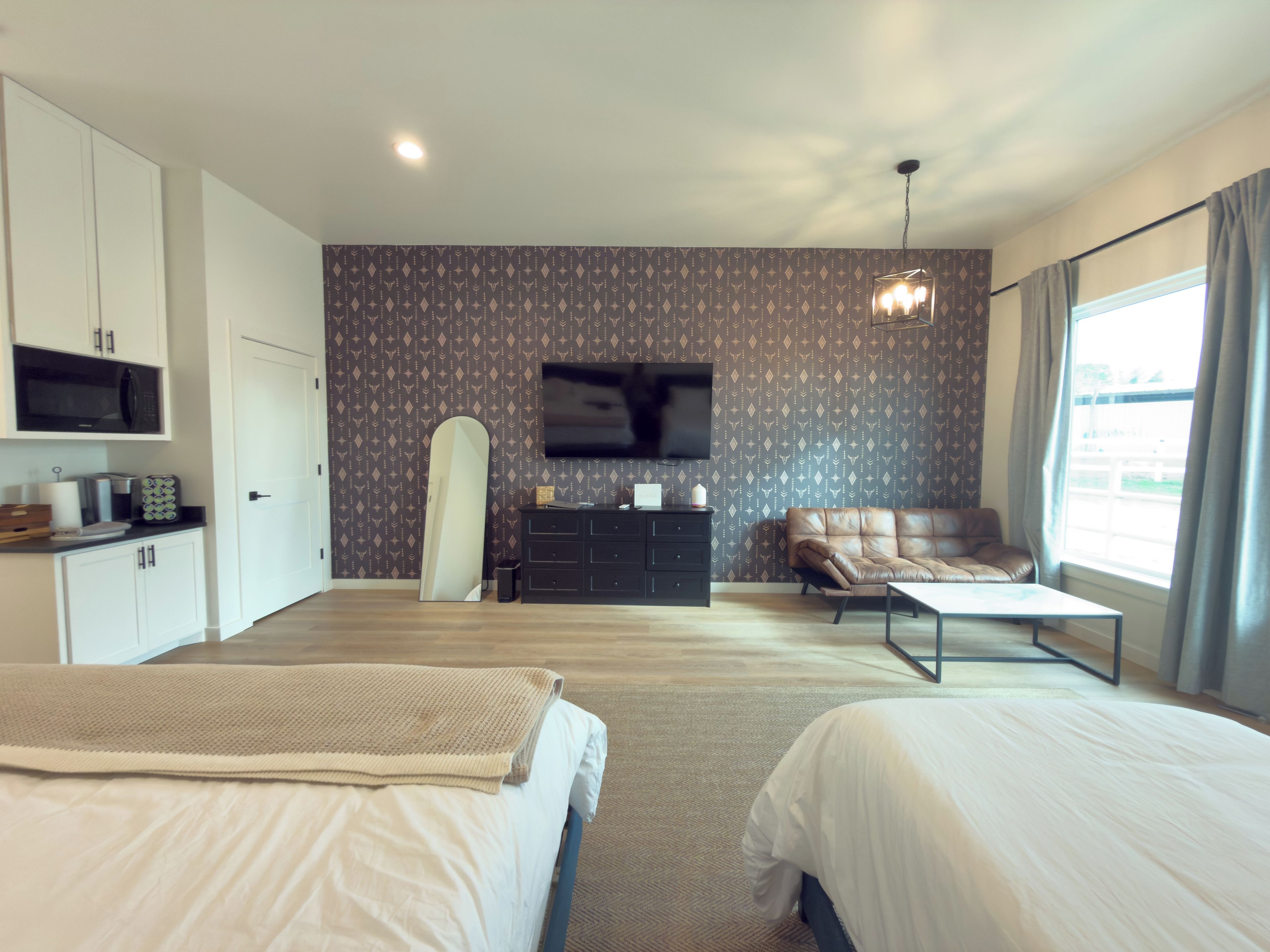 A hotel room with two beds, a television, a sofa, and a desk with a flat-screen TV.