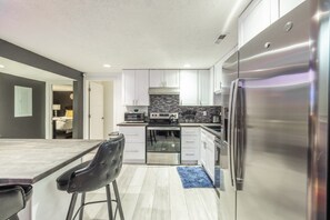 Une cuisine moderne avec des armoires blanches, des appareils en acier inoxydable et un comptoir en marbre.