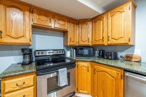 A kitchen with wooden cabinets, a stainless steel stove, a microwave, and a coffee maker. - Midvale Ski Base | Alta, Snowbird & Brighton (Midvale)