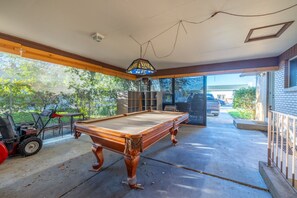 A pool table in a covered outdoor area with a car and a lawnmower in the background. - Midvale Ski Base | Alta, Snowbird & Brighton (Midvale)