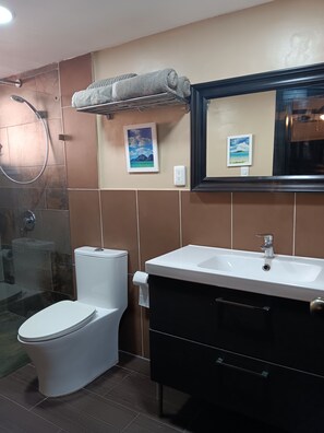 Ein Badezimmer mit Toilette, Waschbecken, Dusche und Handtuchhalter.