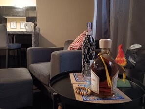 A living room with a sofa, a small round table, a bottle of liquor, and a decorative rooster. - Gazcue Executive Apartment by Peace Corps, UN, Clinics, and Universities (Santo Domingo)