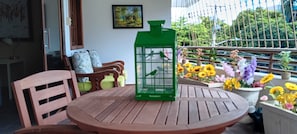 A round wooden table with a green lantern, chairs, and a potted plant with flowers on a balcony. - Gazcue Executive Apartment by Peace Corps, UN, Clinics, and Universities (Santo Domingo)