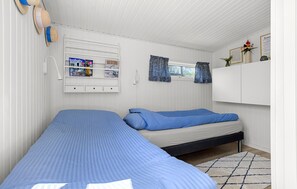 A room with two beds, a shelf with magazines, a window with curtains, and a wall-mounted light fixture. - Beautiful home in Slagelse with WiFi (Slagelse)