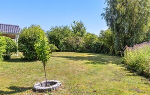 A garden with a circular stone structure, a small tree, and various shrubs. - Beautiful home in Slagelse with WiFi (Slagelse)
