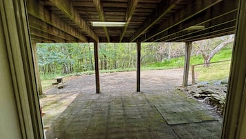 An open wooden structure with a view of a paved area and greenery outside.