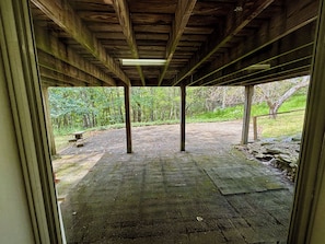An open wooden structure with a view of a paved area and greenery outside.