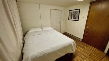 A hotel room with a bed, a door, a framed picture on the wall, and a wooden floor.