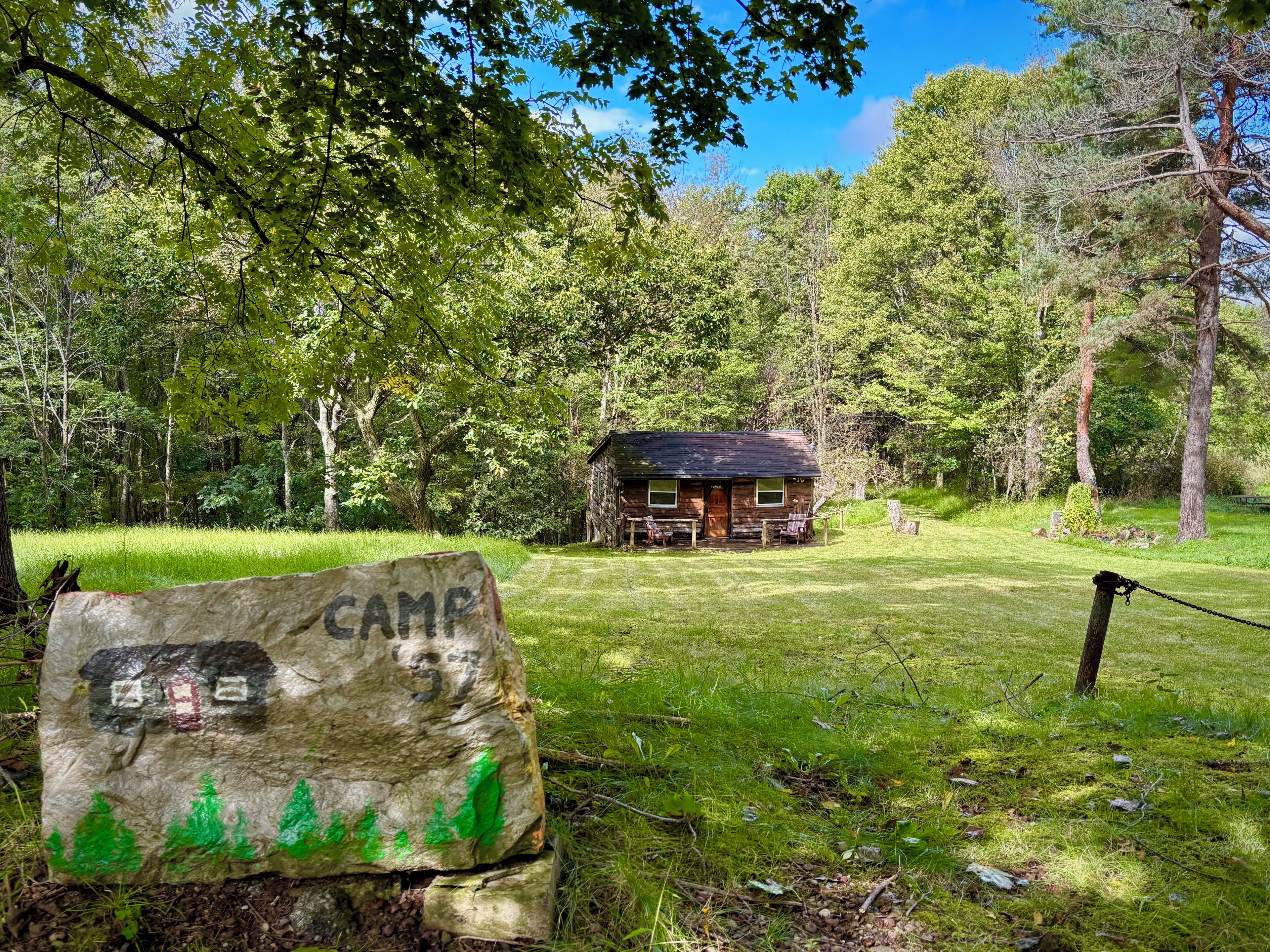 A rustic cabin with a wooden exterior, surrounded by lush greenery and trees.