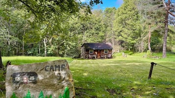 A rustic cabin with a wooden exterior, surrounded by lush greenery and trees.