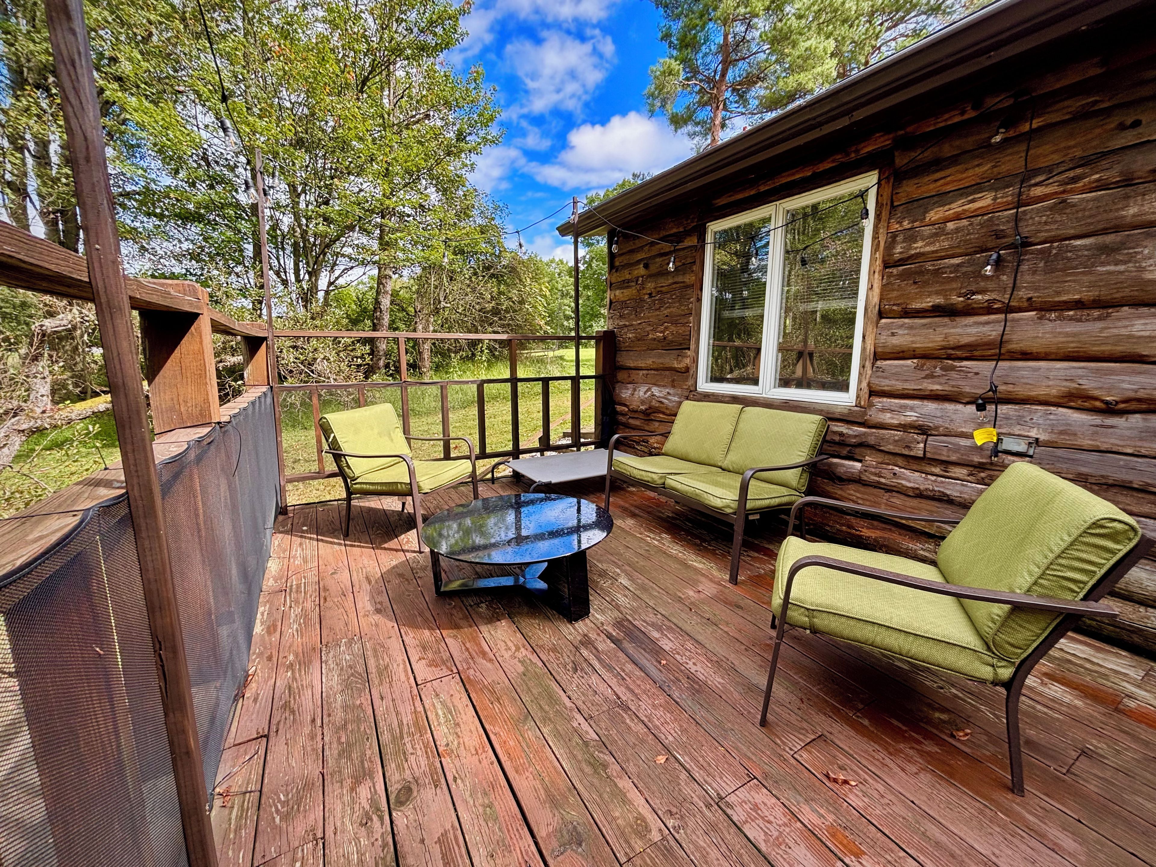 Une cabane en bois dotée d’une terrasse, aménagée avec une table et deux chaises.