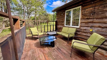 Une cabane en bois dotée d’une terrasse, aménagée avec une table et deux chaises.