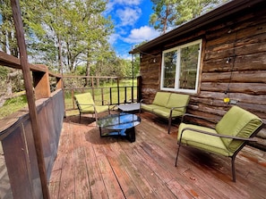 A wooden cabin with a deck, furnished with a table and two chairs.