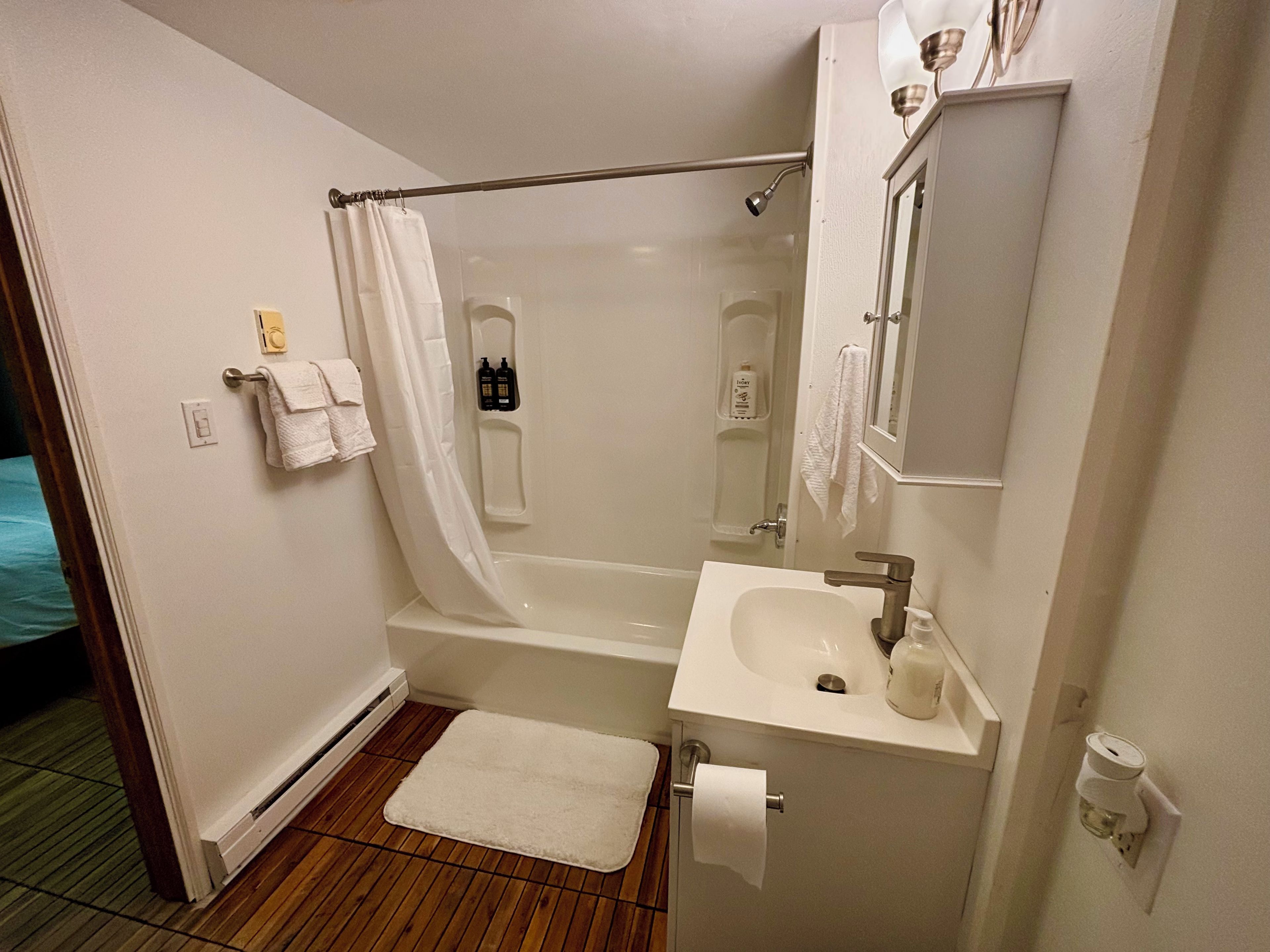 A bathroom with a bathtub, a sink, a mirror, and a shower curtain.