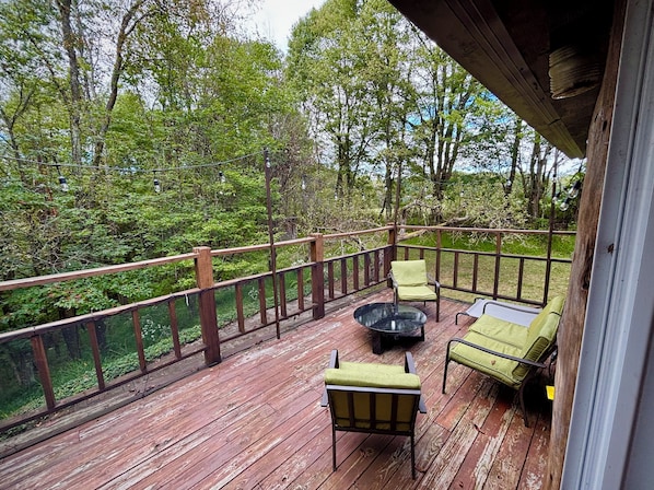 A wooden deck with outdoor furniture, surrounded by trees.