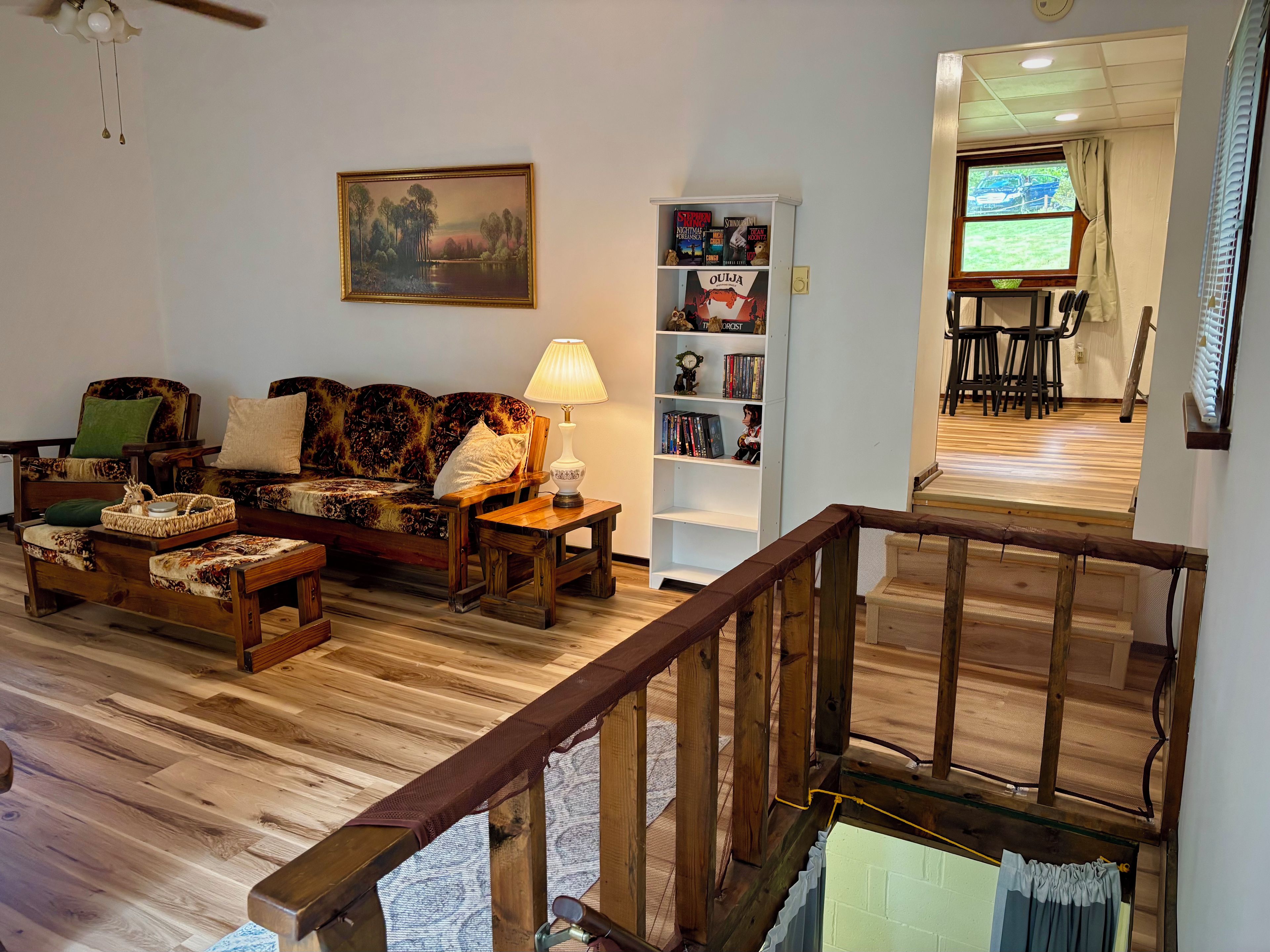 A living room with a sofa, a coffee table, a lamp, a bookshelf, and a painting on the wall.