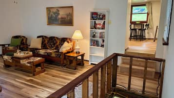 A living room with a sofa, a coffee table, a lamp, a bookshelf, and a painting on the wall.