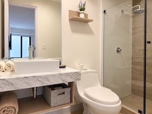 A modern bathroom with a marble sink, toilet, and glass-enclosed shower. - Modern apartment with terrace in Miraflores (101) (Miraflores)