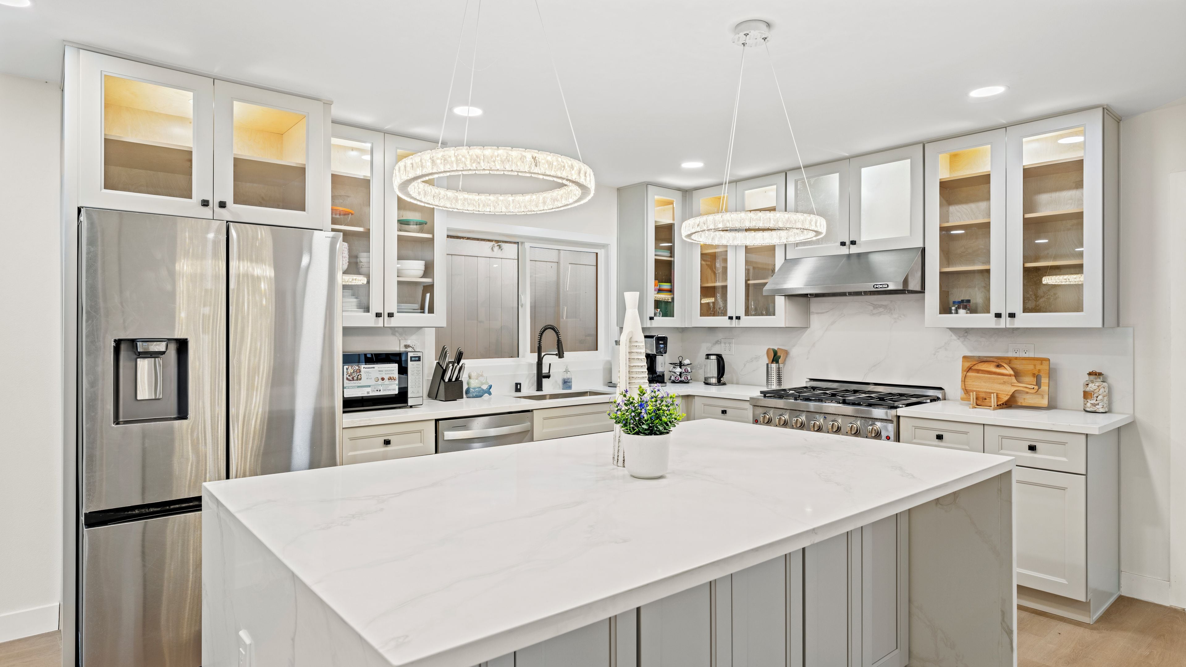 A modern kitchen with a central island, stainless steel appliances, and pendant lighting.