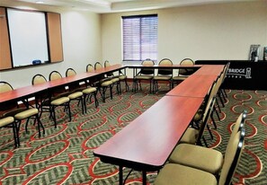A conference room with a long table, chairs, a projector screen, and a window with blinds. - Accessible Suite w/ Kitchen | Free Breakfast! (Houston)