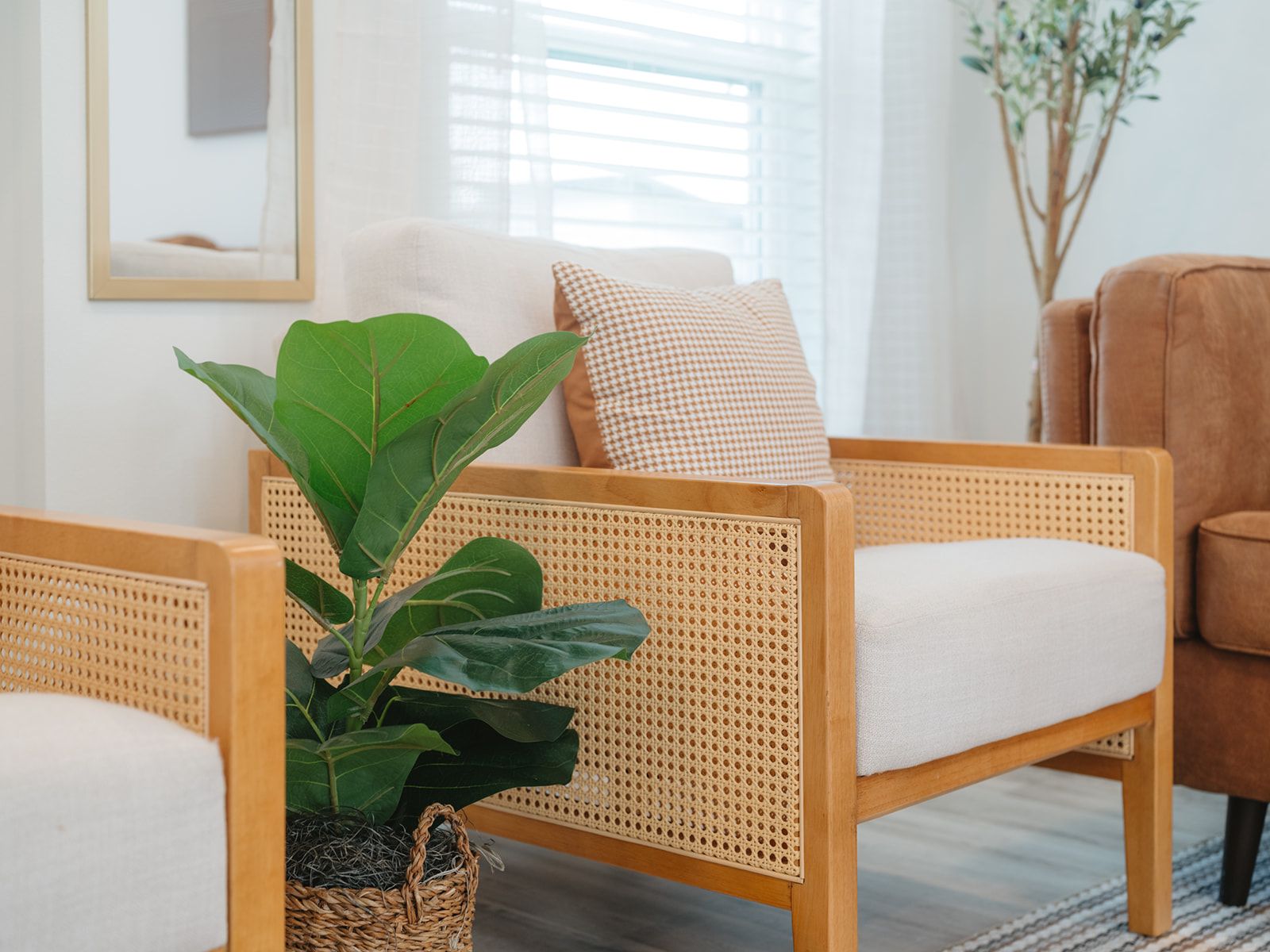 A room with a wicker chair, a cushioned seat, a woven basket with a plant, and a wooden floor.