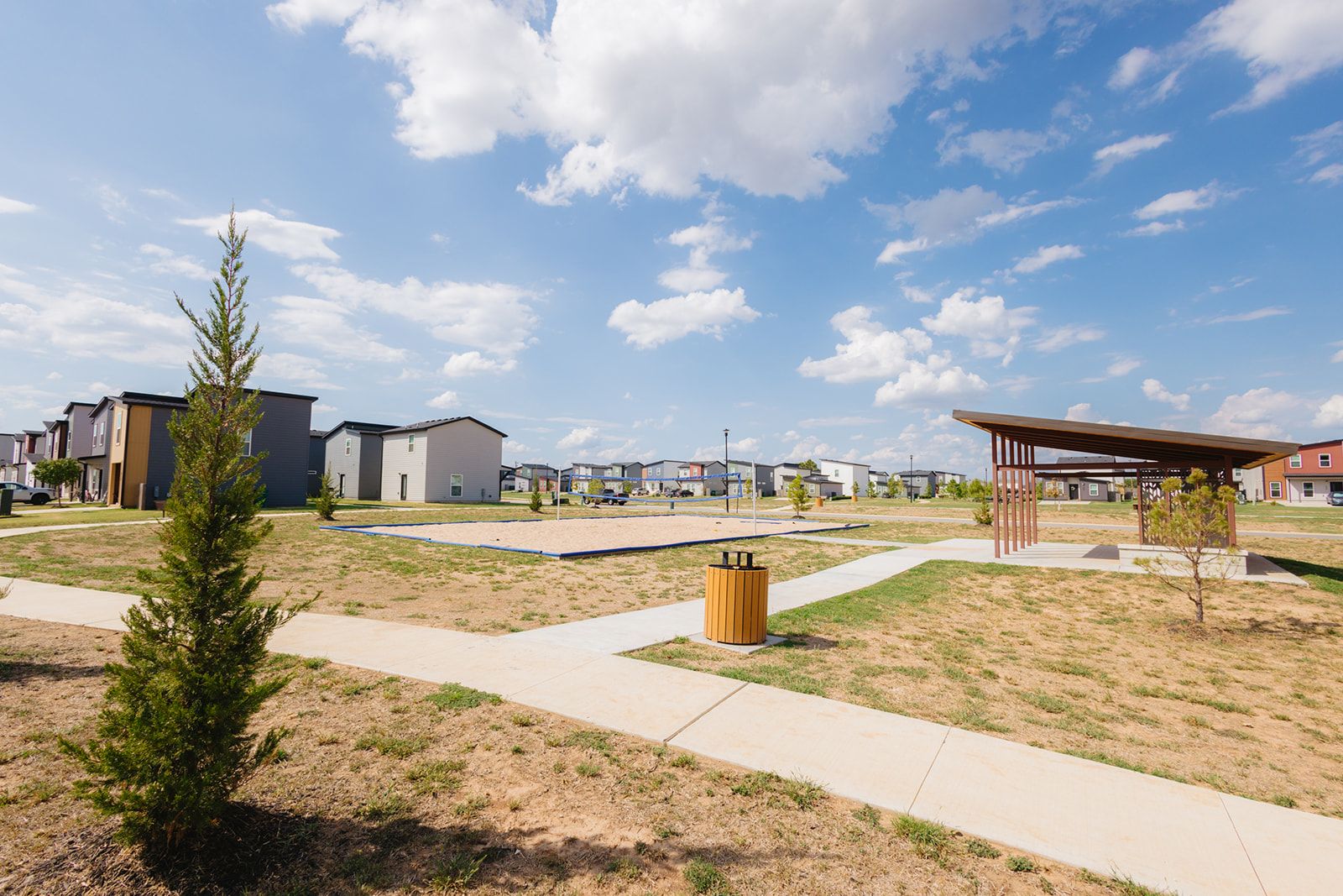 Un quartier résidentiel avec des maisons modernes, une aire de jeux et un pavillon couvert.