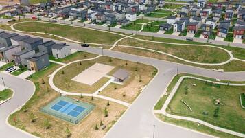 A residential area with houses, roads, and a sports court.