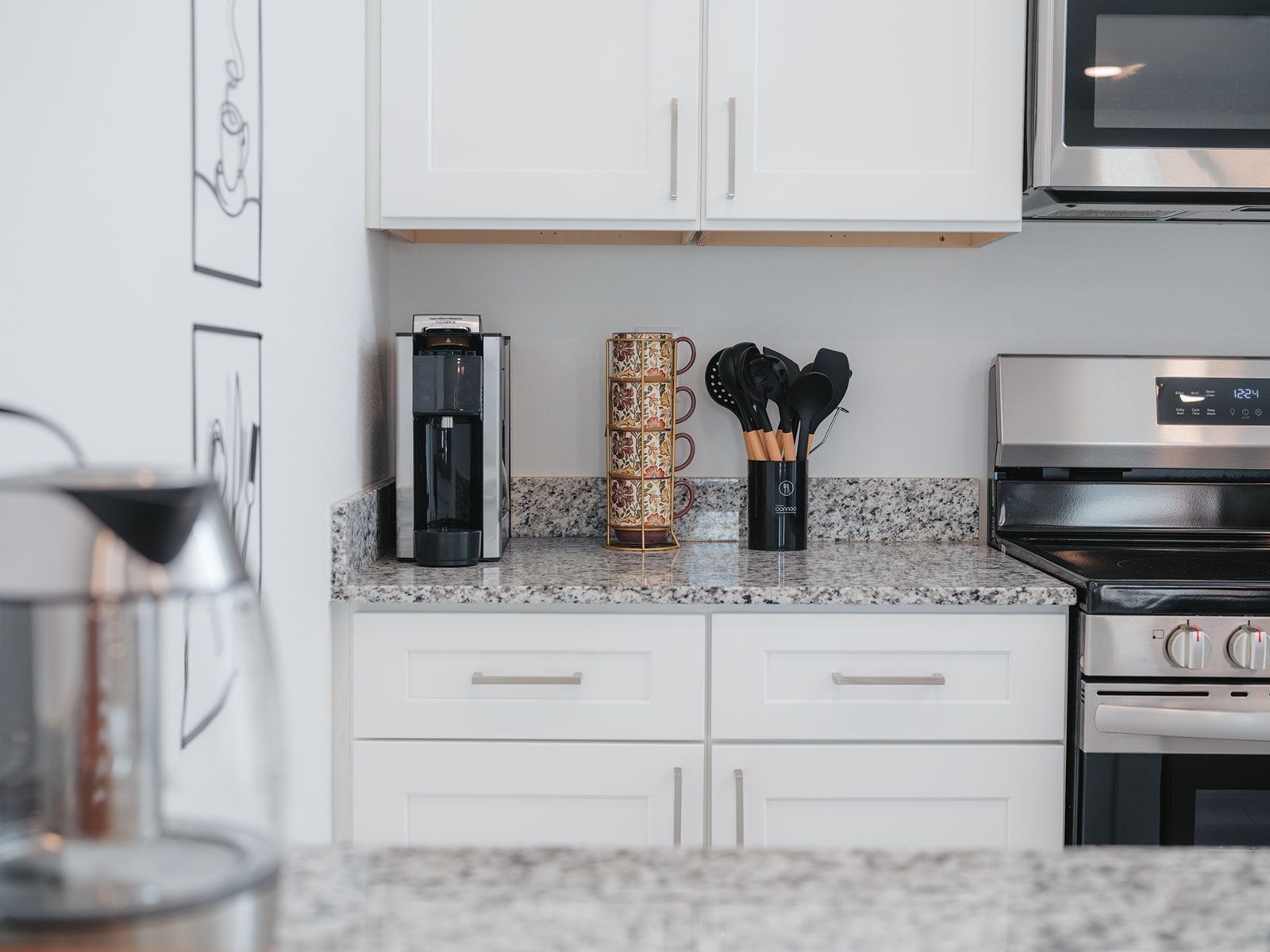 Una cocina con gabinetes blancos, una cafetera, un portavasos y un microondas.
