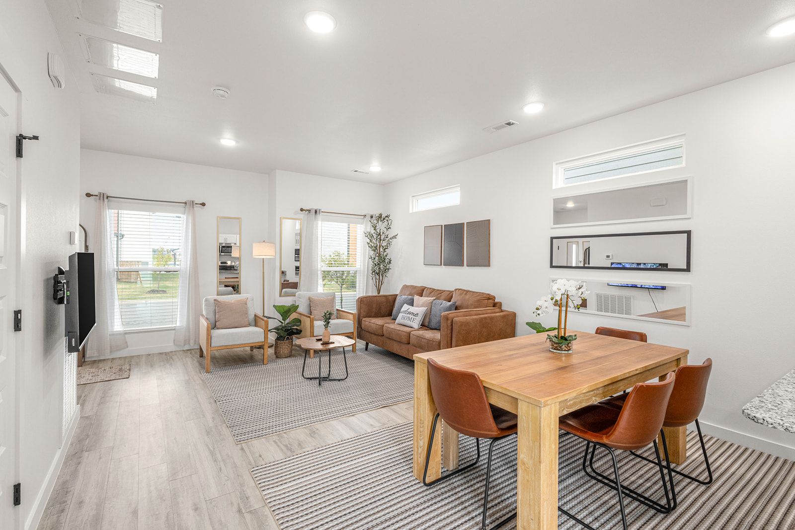 A modern living room with a sofa, chairs, a coffee table, and a dining area with a wooden table and chairs.