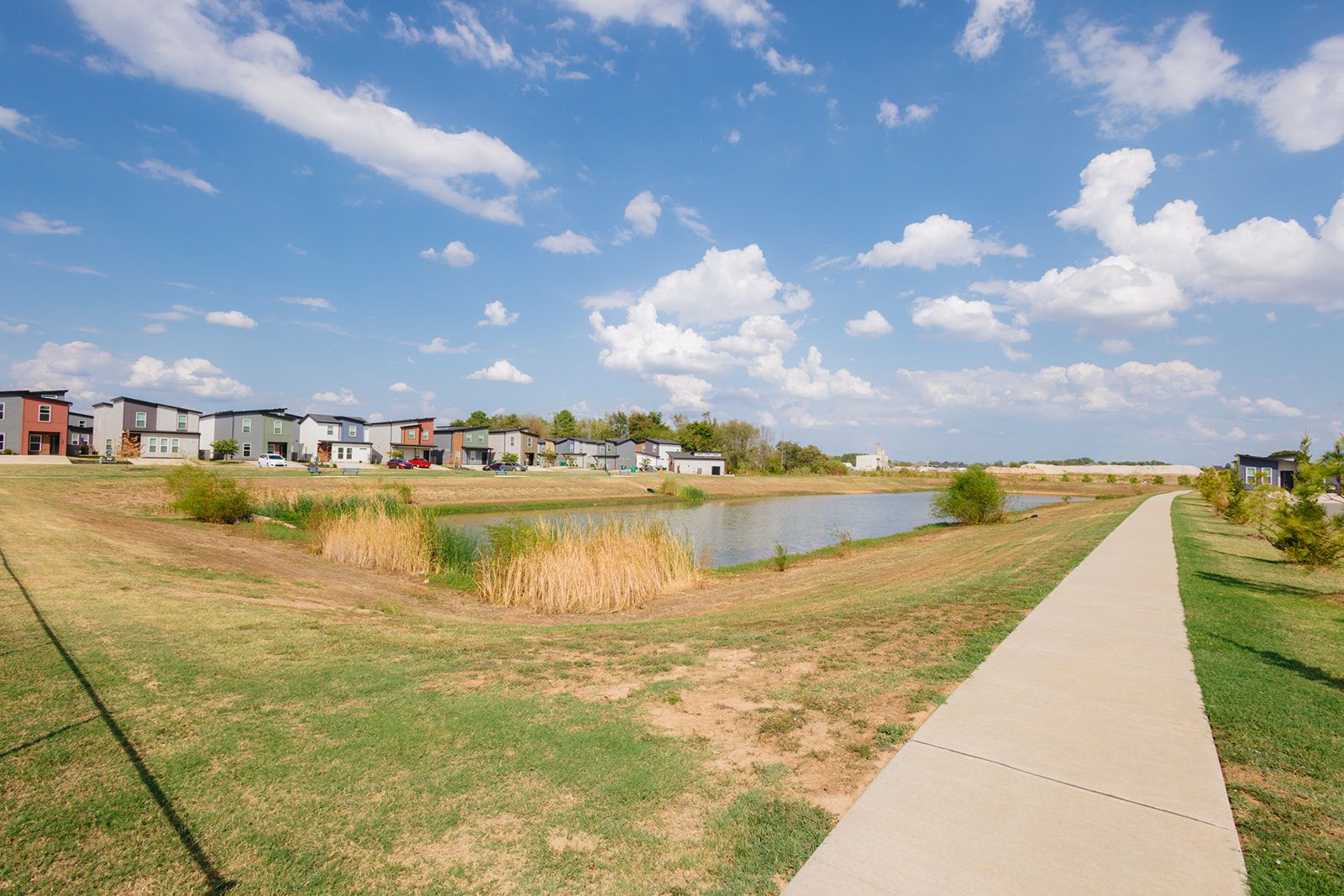 A residential area with houses, a pond, and a walking path.