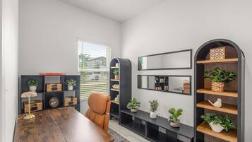 A modern office space with a wooden table, a leather chair, and built-in shelving with potted plants.
